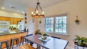 A modern kitchen with wooden cabinets, a central island, and a dining area with a bench and chairs. - Pool Access! Amazing Mtn Retreat in Mercersburg (Mercersburg)