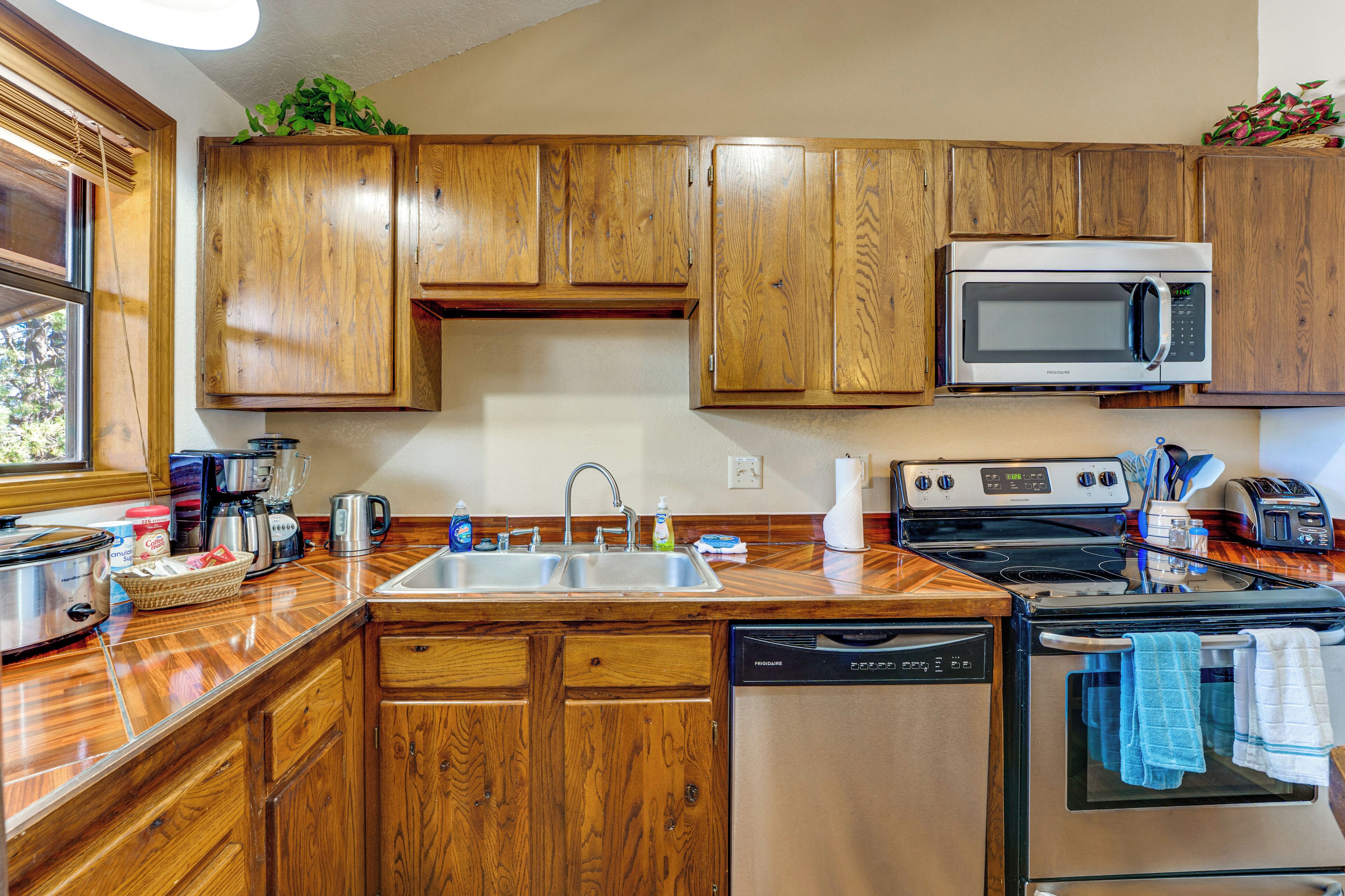 A kitchen with wooden cabinets, stainless steel appliances, a dishwasher, and a window.
