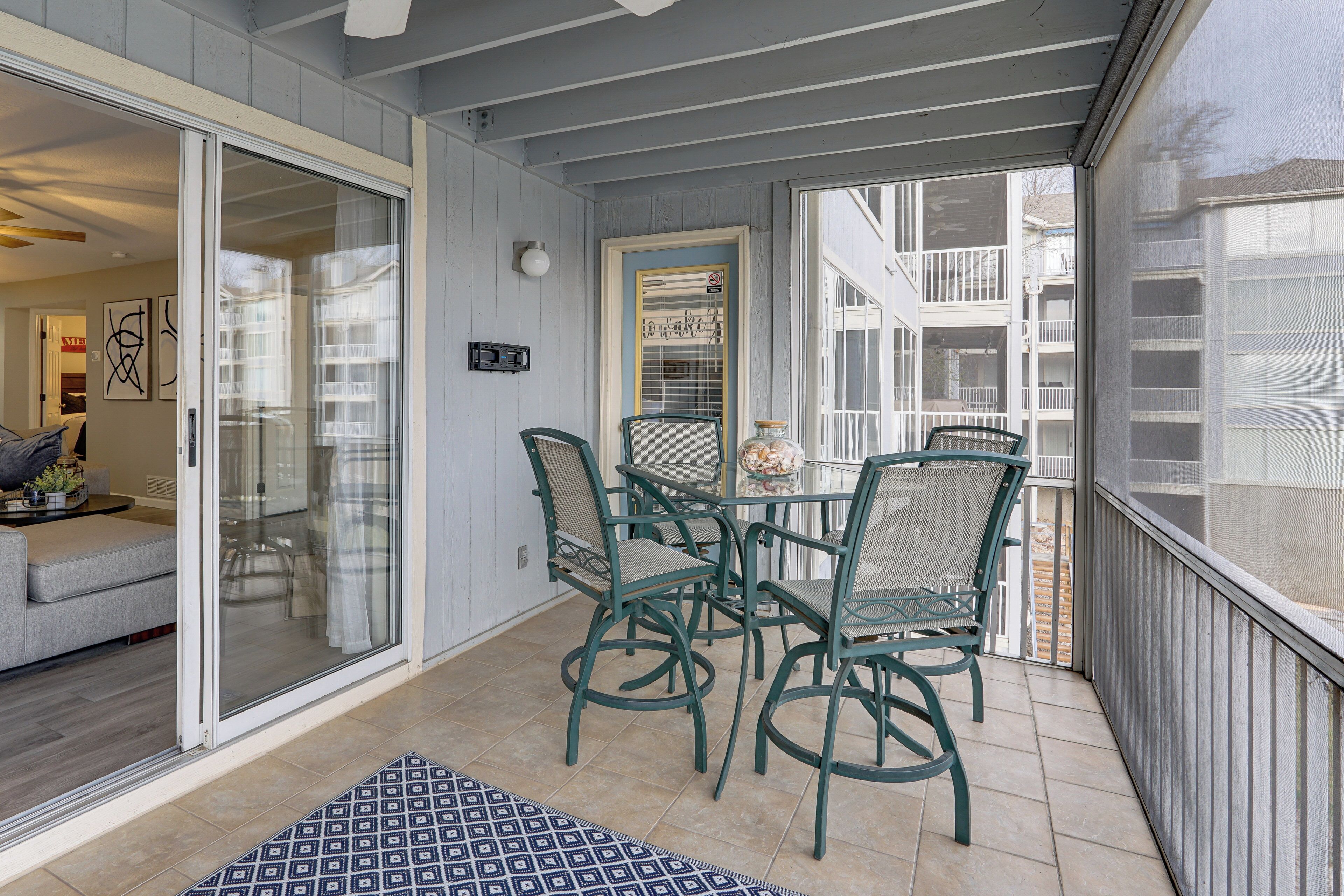 Un patio couvert avec une porte-fenêtre coulissante donnant sur un salon, une petite table avec des chaises et un vase décoratif.