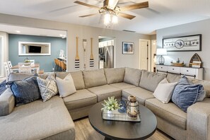 Ein Wohnzimmer mit Ecksofa, Couchtisch und Deckenventilator.