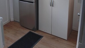 Ett kompakt kök med ett kylskåp i rostfritt stål, ett vitt skåp och ett fönster med utsikt.