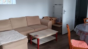 Ett vardagsrum med en soffa, ett soffbord, en trästol och en dörr som står på glänt och leder in till ett annat rum.