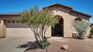 A single-story house with a garage, a front door, and a small tree with red flowers. - 5 Mi to Catalina State Park! Desert Haven w/ Views (Tucson)
