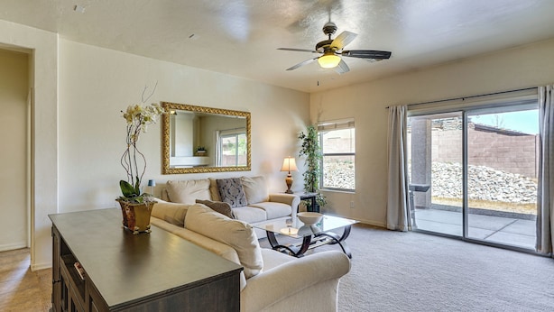 A living room with a sofa, coffee table, and a cabinet. There is a ceiling fan, a large mirror, and a sliding glass door leading to an outdoor area. - 5 Mi to Catalina State Park! Desert Haven w/ Views (Tucson)