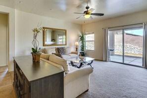 A living room with a sofa, coffee table, and a cabinet. There is a ceiling fan, a large mirror, and a sliding glass door leading to an outdoor area. - 5 Mi to Catalina State Park! Desert Haven w/ Views (Tucson)