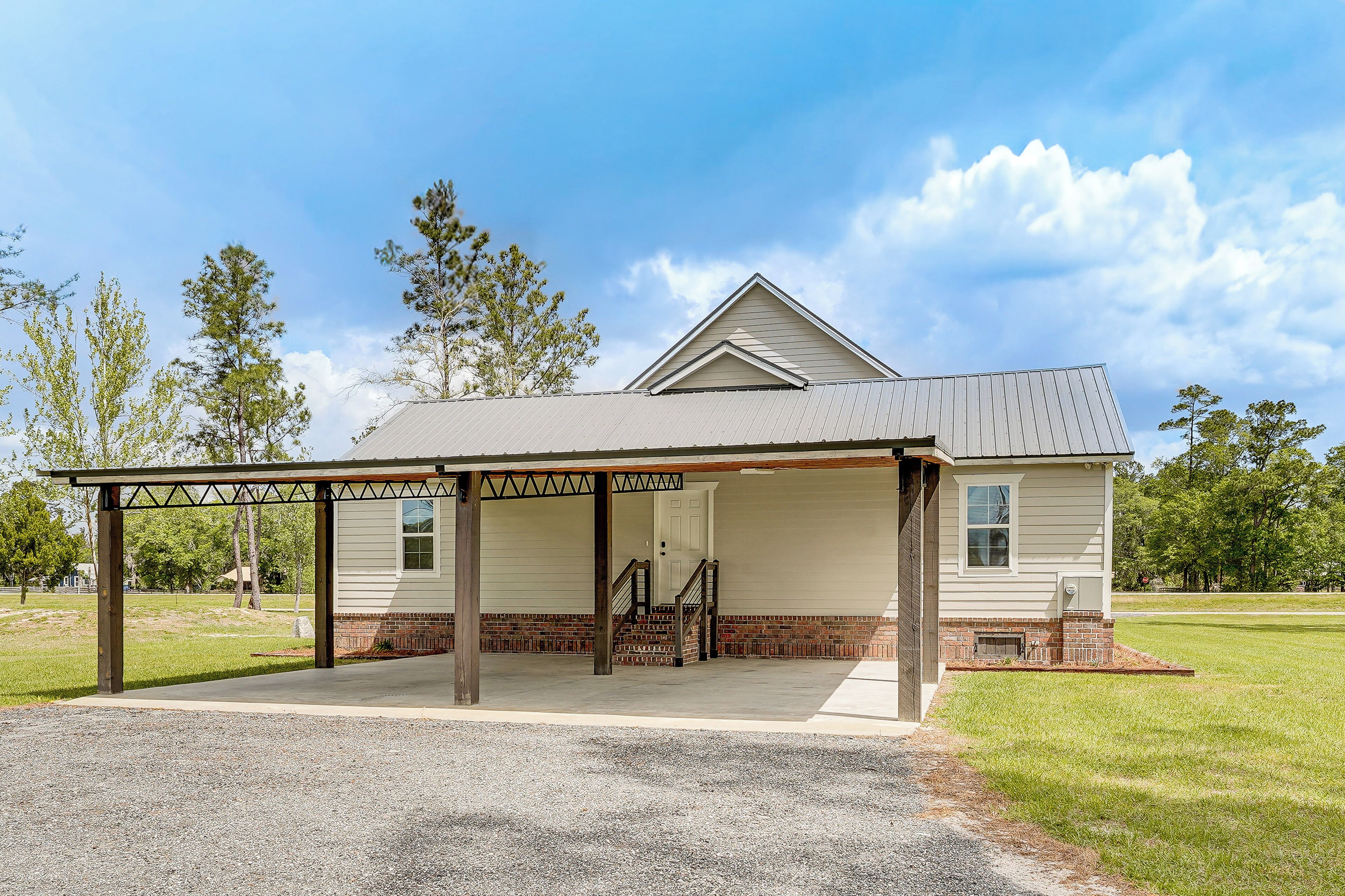 A single-story house with a covered porch, a brick foundation, and a clear sky.