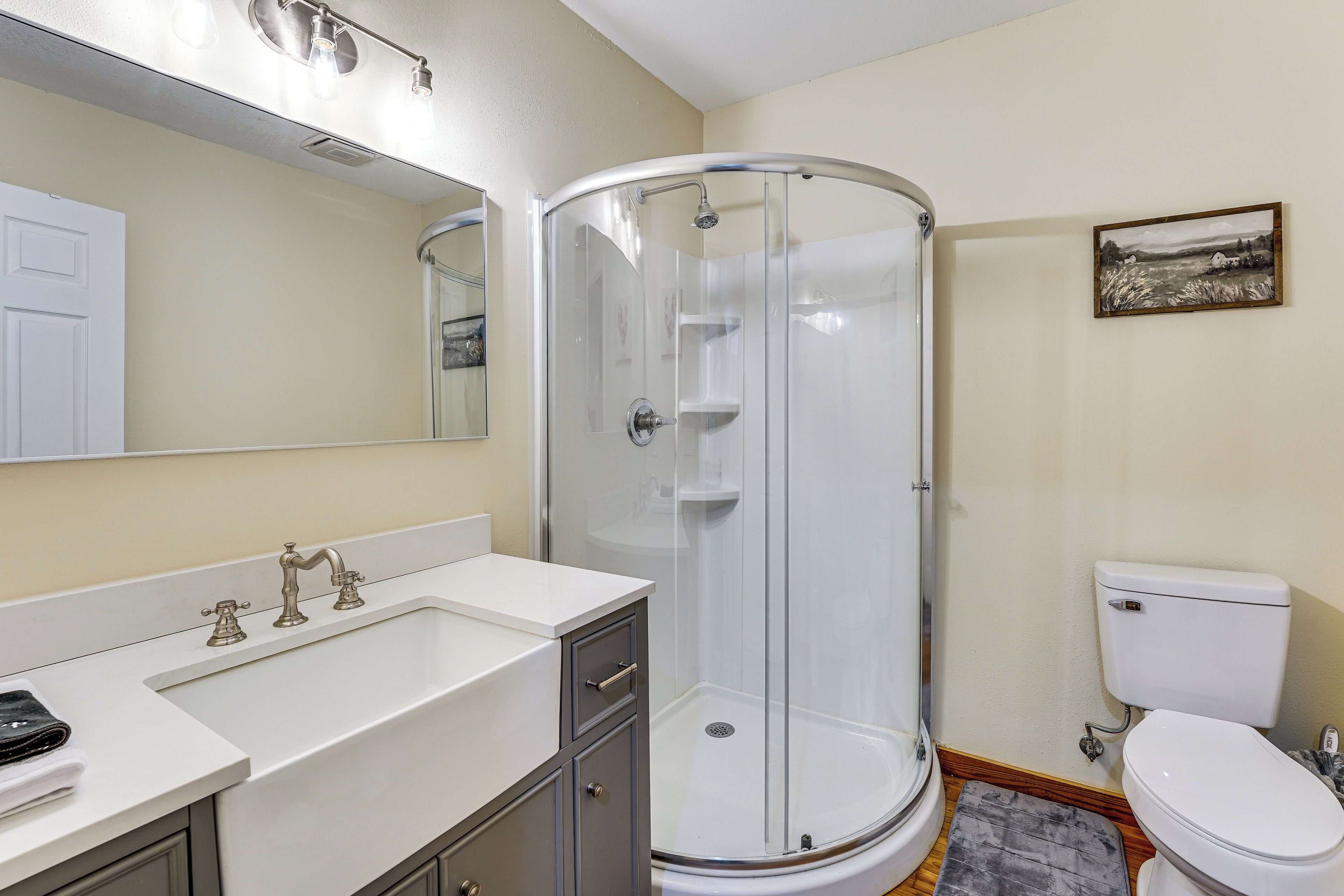 Een badkamer met een douchecabine van glas, een wit wastafelmeubel en een toilet.