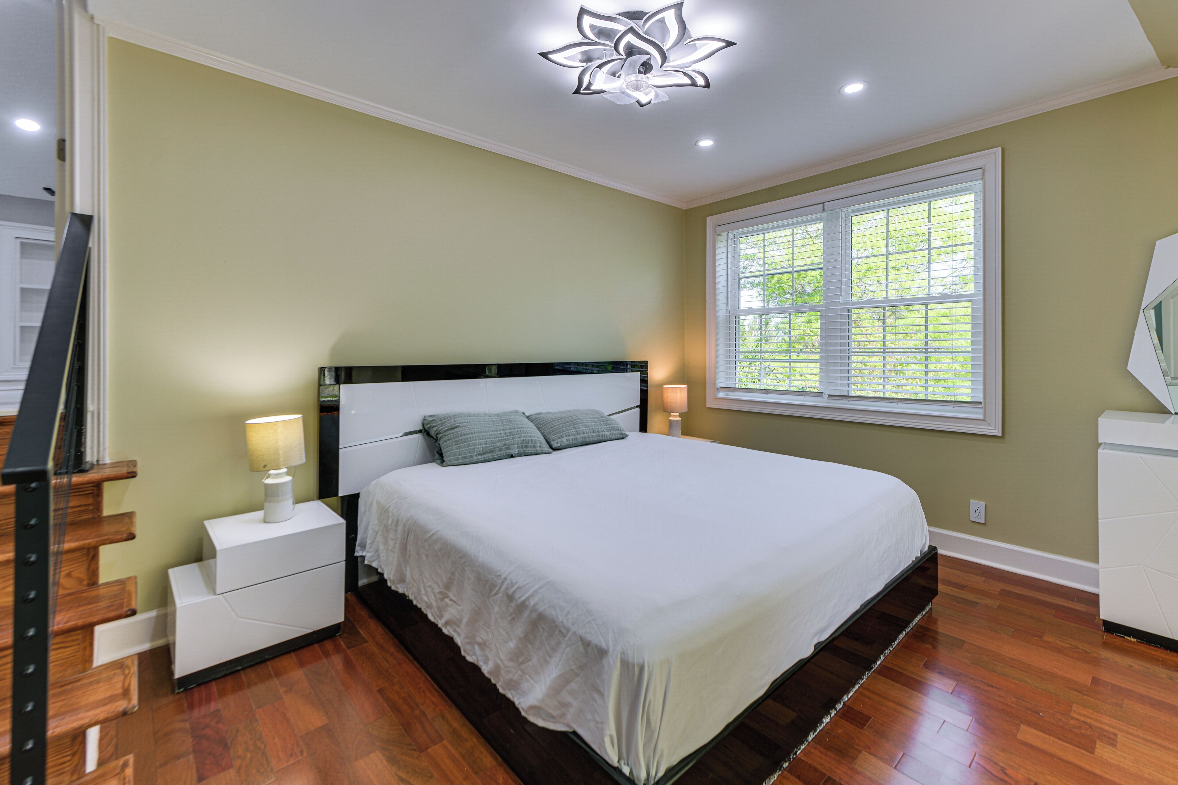 A bedroom with a bed, nightstands, a window, and a ceiling light fixture.