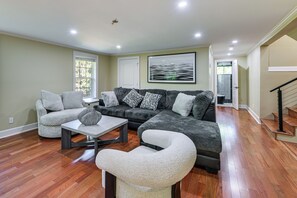 Una sala de estar con un sofá, sillones, una mesita de centro y un cuadro en la pared.