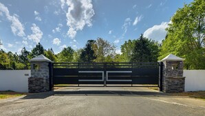 Een poort met een stenen muur, een heldere lucht en bomen op de achtergrond.