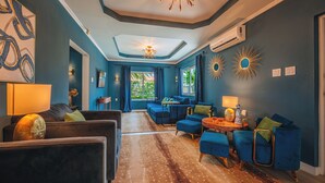 Ein Zimmer mit einer Couch, Sesseln, einem Couchtisch und einer Chandelier.