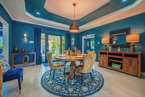 A dining area with a round table, chairs, a wooden console, and a blue patterned rug. - Boutique Villa w/ Private Pool Near Arashi Beach (Noord)