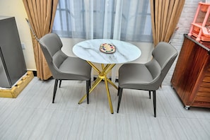 A room with a round table, two chairs, a television, and a wooden cabinet.
