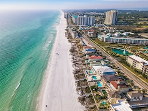 An aerial view of a coastal resort with a long beachfront, high-rise hotels, and a pool area. - Just Beachy | Luxe Home, 400ft to Beach, Private Pool, Spa + 6 Bikes (Miramar Beach)