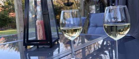 Two wine glasses on a glass table with a lantern and a view of trees.