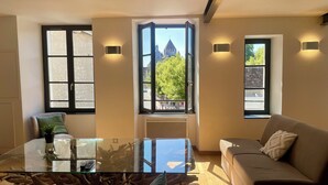 A modern living room with a glass coffee table, a sofa, and two windows with black frames. - Appartement du Châtel (Provins)