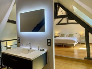 A modern bathroom with a large mirror, a sink, and a shower area. - Appartement du Châtel (Provins)