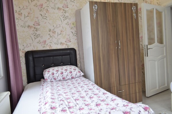 A bedroom with a bed, a wooden wardrobe, and a white door.