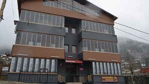 A multi-story building with a flat roof, large windows, and a sign that reads 'ÖZKAN.' - Özkan Pansiyon (Caykara)