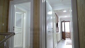 A hallway with white doors, a metal handrail, and a patterned carpet. - Özkan Pansiyon (Caykara)