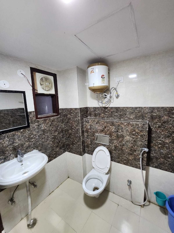 Un baño con lavamanos, inodoro y un calentador de pared.