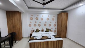 A bedroom with a bed, wooden wardrobe, ceiling fan, and a patterned wall. - Hotel Yashobhoomi Stay Inn (New Delhi)