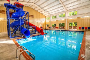 An indoor swimming pool with a blue and red water slide structure.