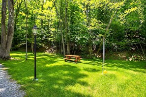 A park with a wooden bench, a lamp post, and a grassy area.