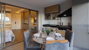 Ein modernes, kompaktes Wohnzimmer mit Essbereich, Küchenzeile und Schlafzimmer.
