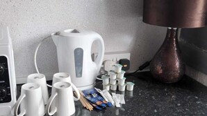 A kitchen counter with a coffee maker, a kettle, a lamp, and some packaged food items. - The Galloway Hotel  (Blackpool)