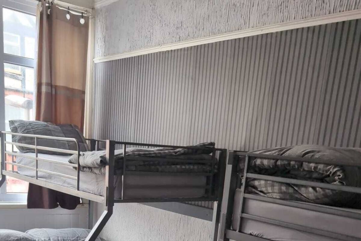 A room with bunk beds, a window with curtains, and a visible door.