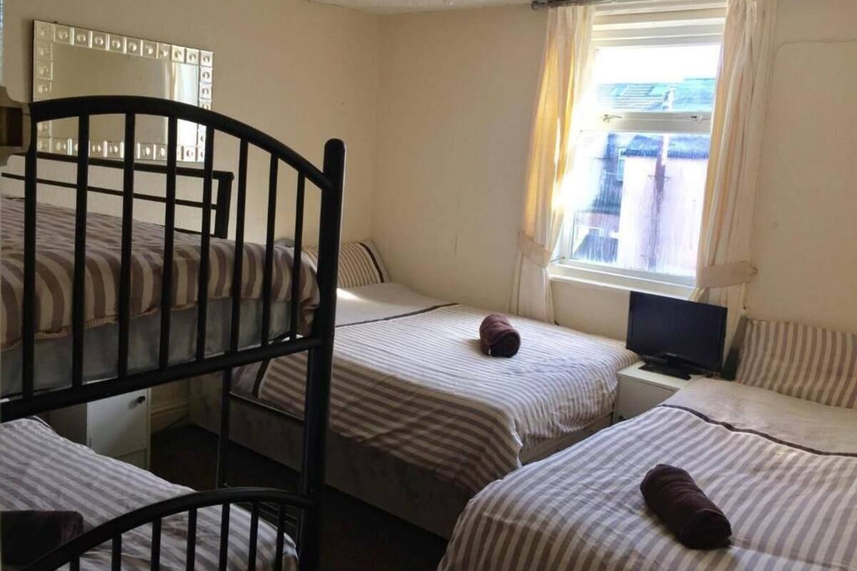 A room with bunk beds, a television, a window with curtains, and a mirror on the wall.
