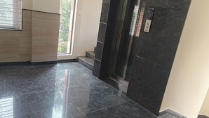 A modern interior with a polished marble floor, a staircase, and a door leading to another area.