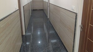 A hallway with a polished floor, white walls, and a wooden door on the right.