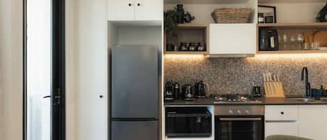 A modern kitchen with a built-in refrigerator, oven, and stove. There are cabinets, a sink, and various kitchen appliances.