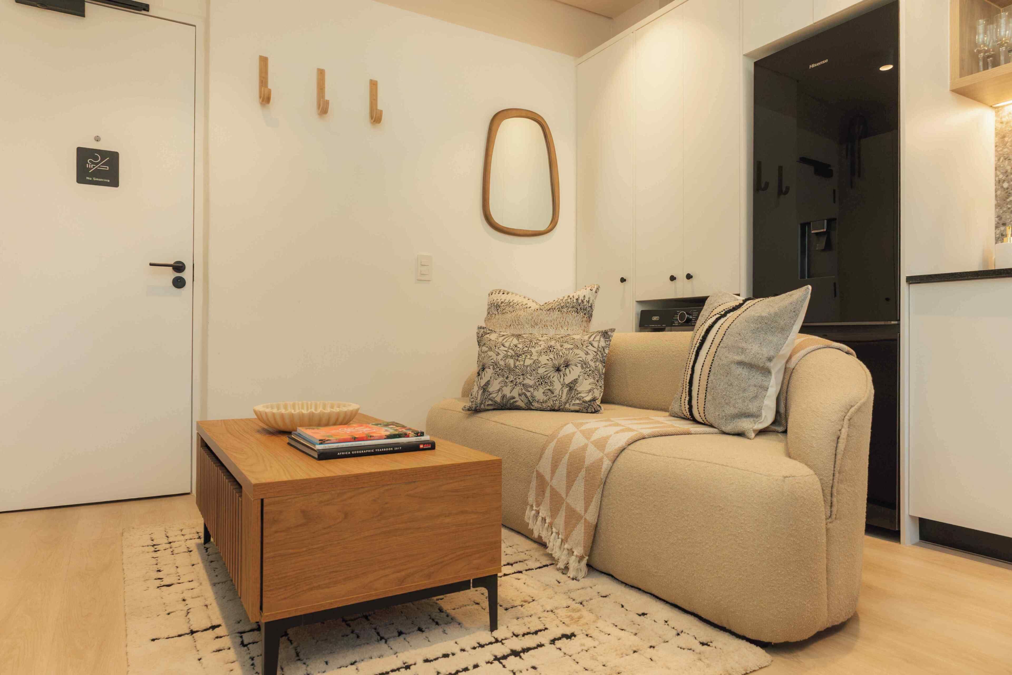 Un espacio habitable compacto con un sofá, una pequeña mesa de madera, un cuenco y algunos libros.