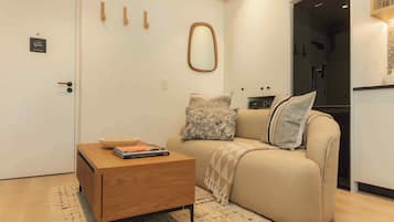 Un espacio habitable compacto con un sofá, una pequeña mesa de madera, un cuenco y algunos libros.
