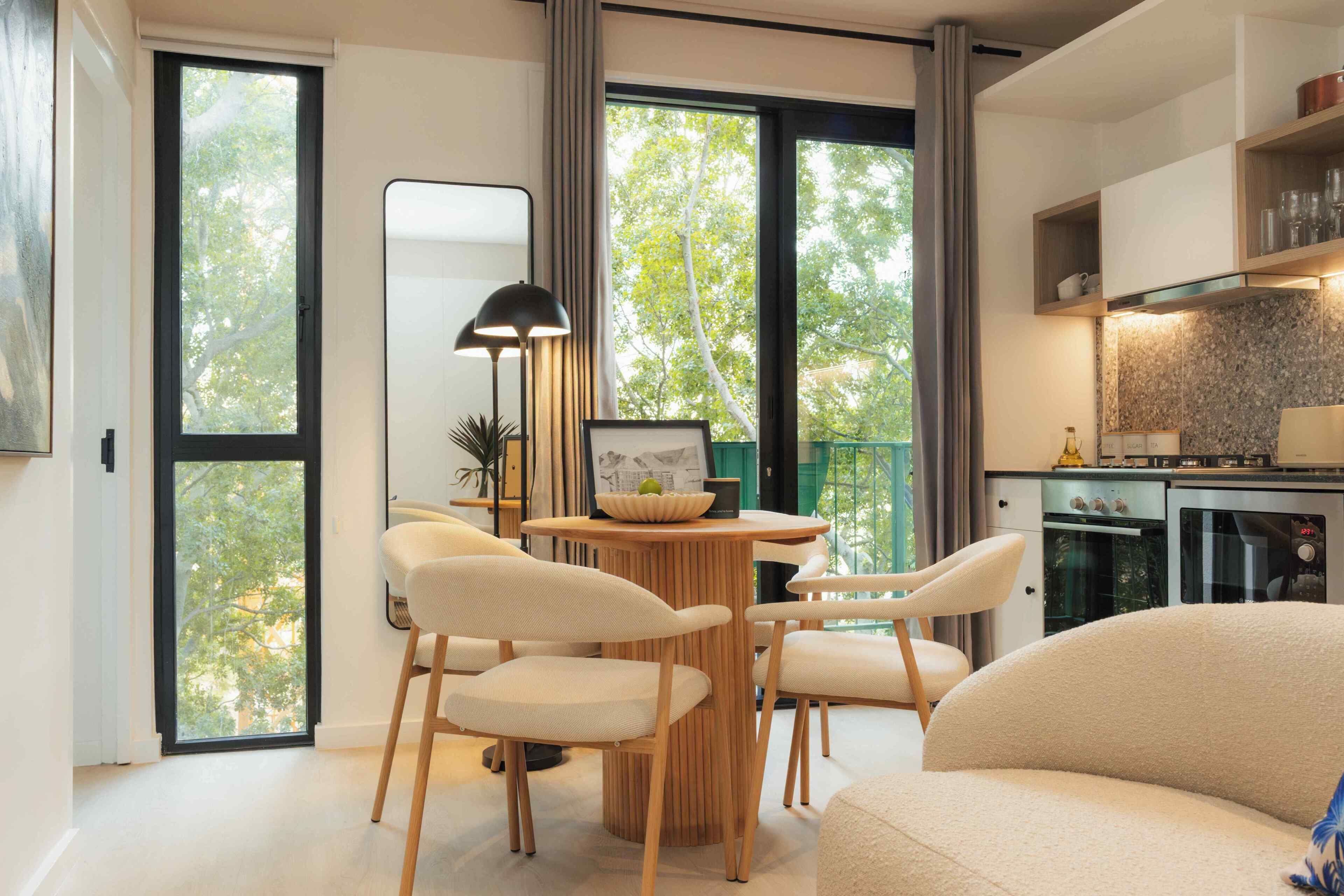 A modern living room with a dining area, large windows, and a kitchen.