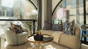 A modern living room with a curved sofa, a round coffee table, and decorative pillows. - TEN on V - Fluent Serviced Apartments (Cape Town)