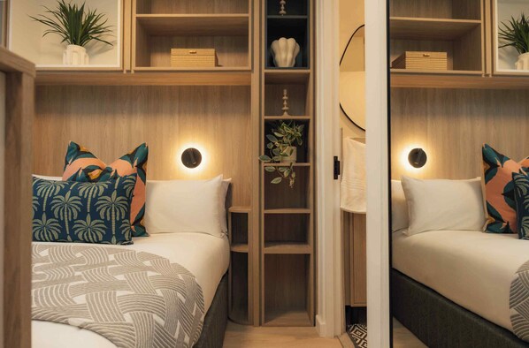 Een slaapkamer met een bed, kussens, een nachtkastje, een garderobe en een spiegel.