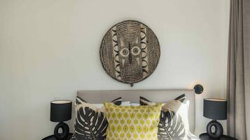 A bed with a headboard, two bedside tables, and a wall-mounted decorative piece.