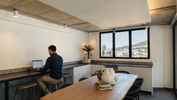 A person working at a desk with a laptop in a modern kitchen area with a view of a cityscape.