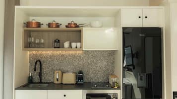 A compact kitchen with a built-in stove, a coffee maker, and a refrigerator.