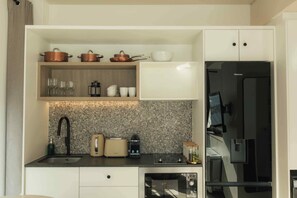 Una cocina compacta con estufa integrada, cafetera y refrigerador.