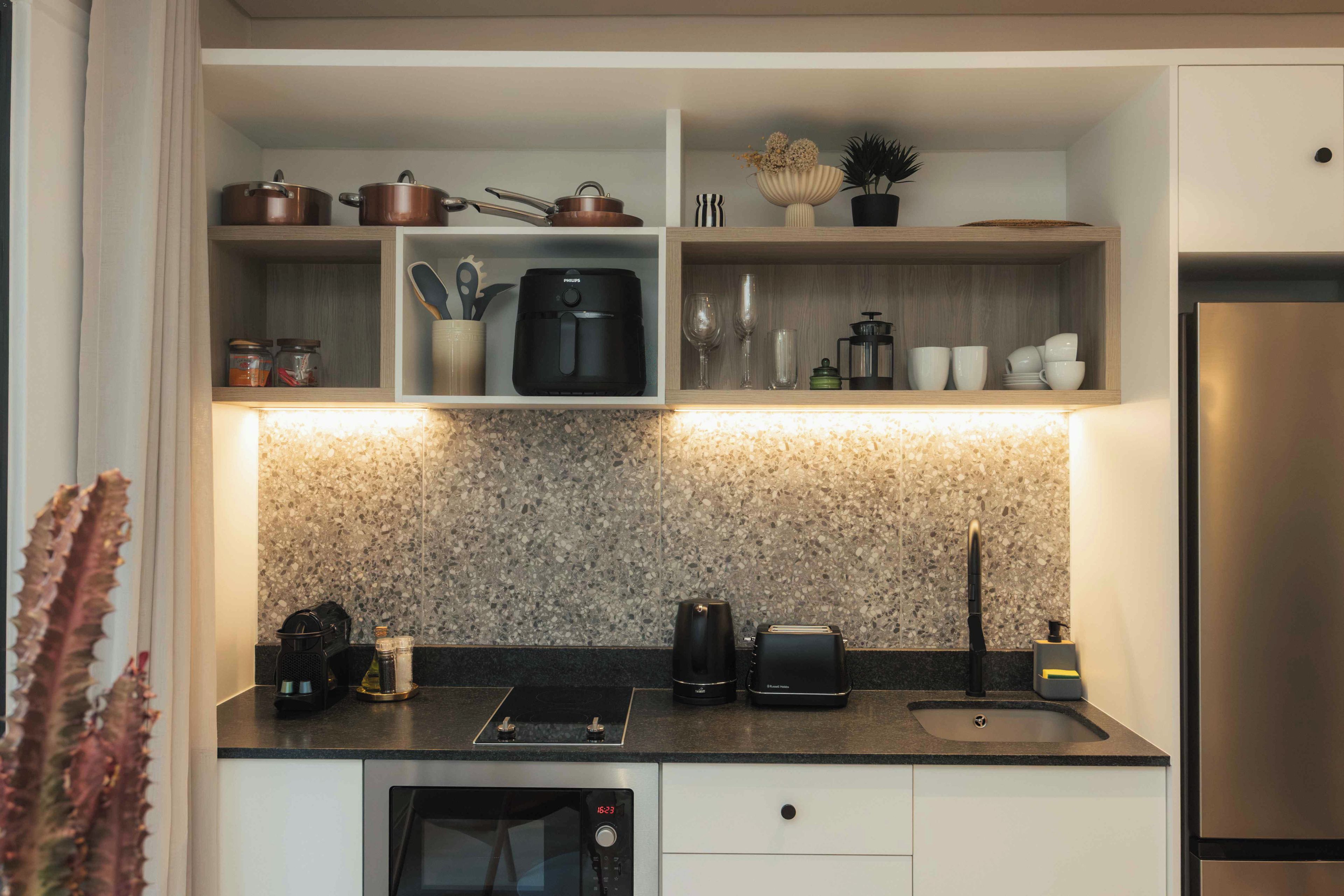 Una cocina moderna con electrodomésticos integrados, encimera de granito y un refrigerador de acero inoxidable.