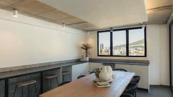 Un comedor con una mesa larga, sillas y vistas a un paisaje urbano a través de amplios ventanales.