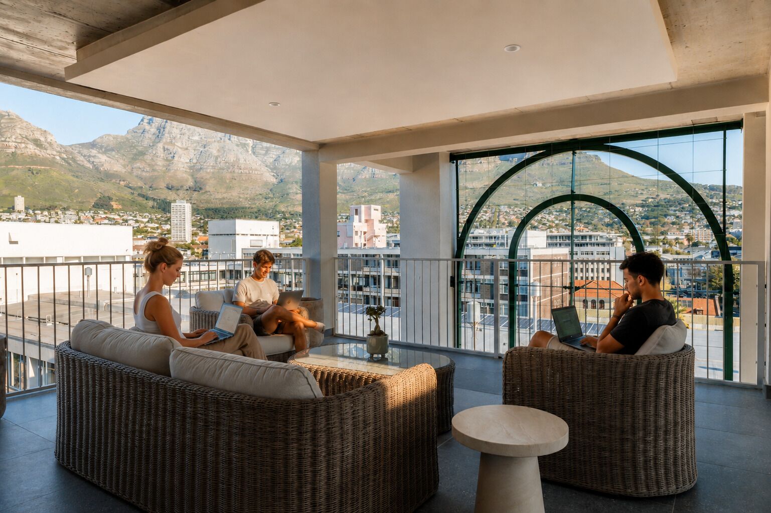 A balcony with wicker furniture, a round table, and a view of a mountainous landscape.