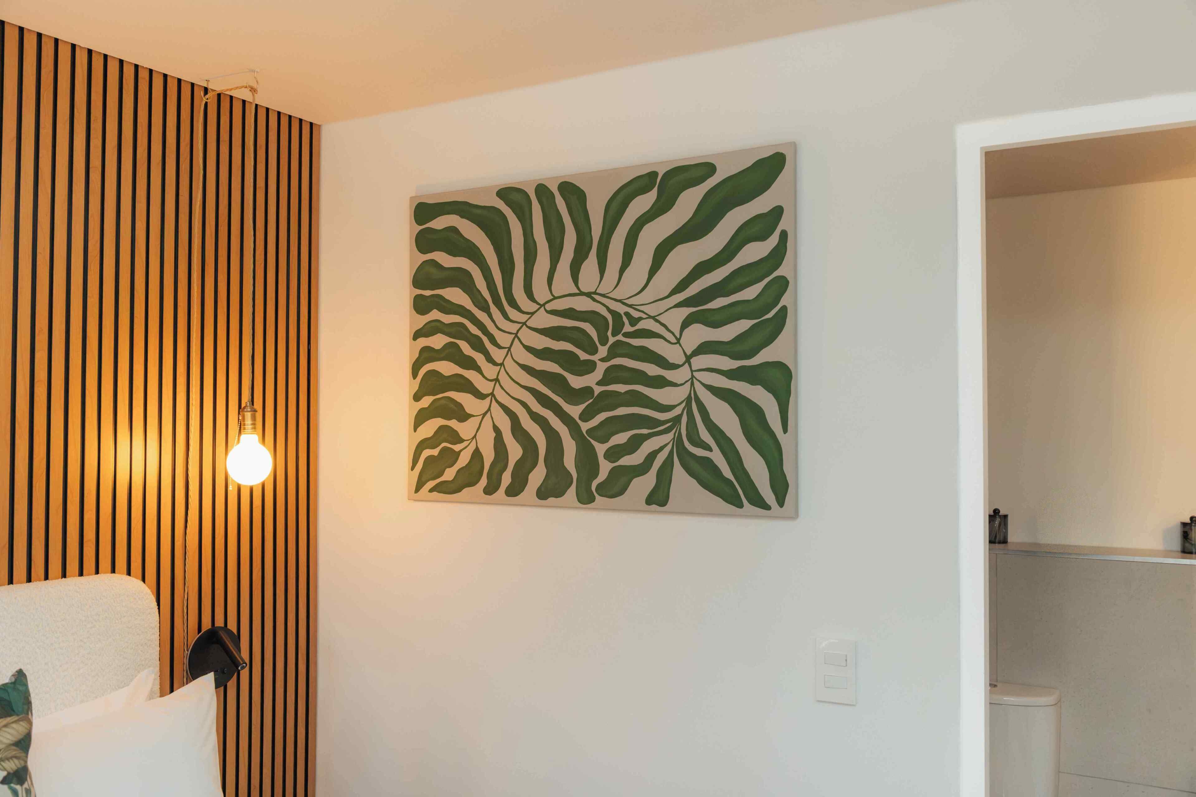 Una stanza con parete in listelli di legno, una parete bianca decorata con un motivo a foglia verde, una sedia bianca e un lampadario.