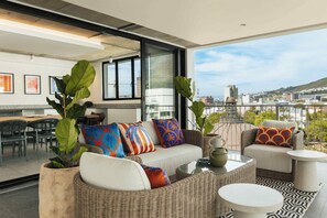 A modern living room with a sofa, chairs, and a dining area. - TEN on V - Fluent Serviced Apartments (Cape Town)