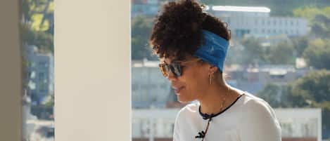 Una persona sentada a una mesa con una computadora portátil, usando una blusa blanca de manga larga, pantalones negros y una diadema azul.